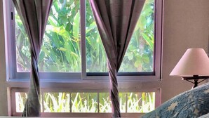 Ein Zimmer mit einem Bett, einem Vorhangfenster und einer Lampe.
