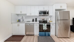 Una cocina moderna con armarios blancos, electrodomésticos de acero inoxidable y lavavajillas.