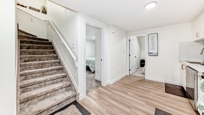 Un interior moderno con una escalera empapelada, suelo de madera, una zona de cocina y una cita inspiradora enmarcada en la pared.