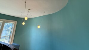 Ein Zimmer mit türkisfarbenen Wänden, einer weißen Decke und drei hängenden, kugelförmigen Leuchten.