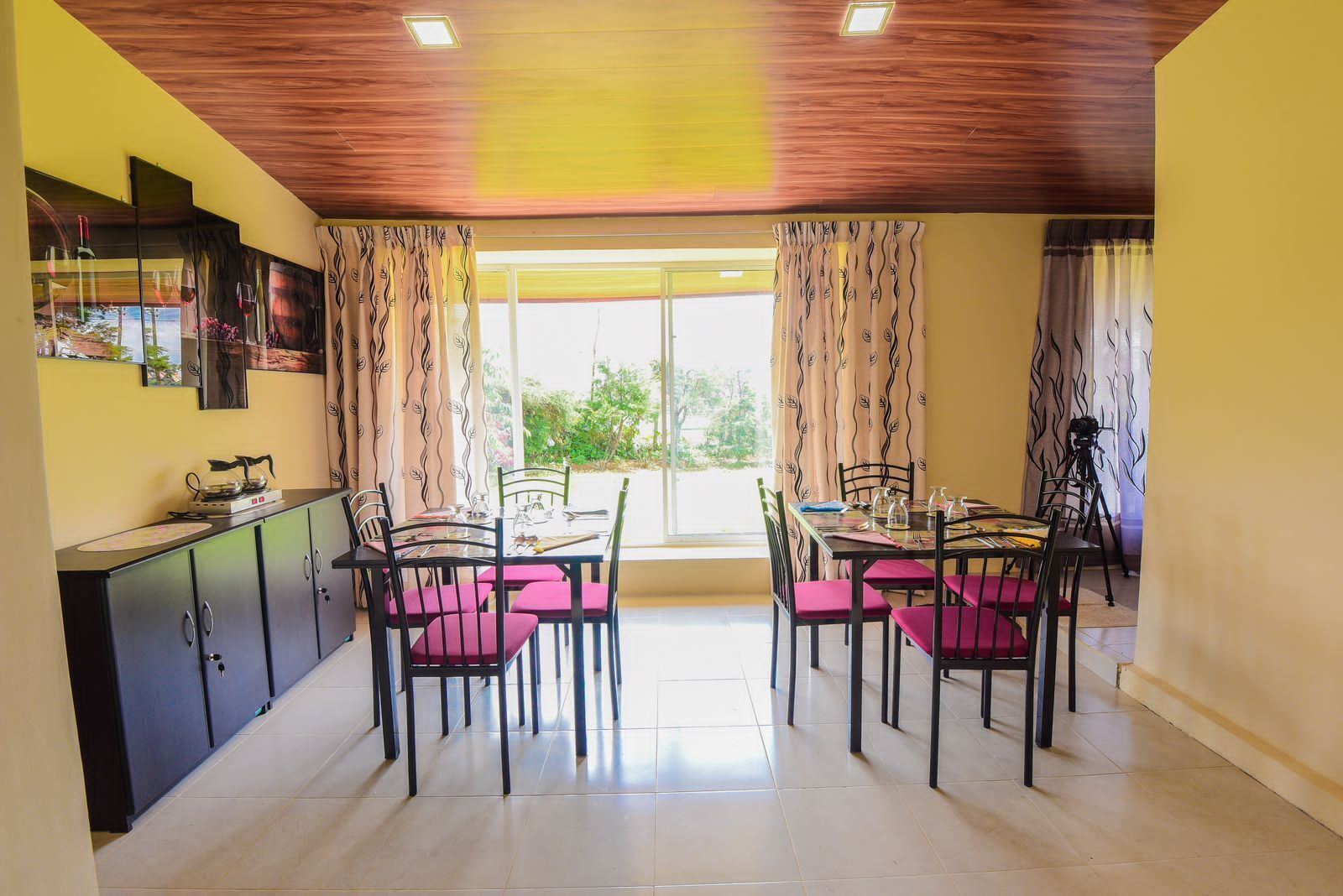 A dining area with a table and chairs, a kitchen counter, and a window with curtains.