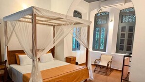 A room with a four-poster bed, a chair, and a small table. - Stuart House Tangalle (Tangalle)