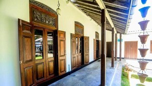 A covered corridor with wooden doors and a hanging water feature. - Stuart House Tangalle (Tangalle)