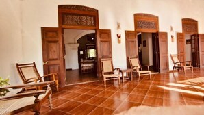 A spacious lobby with wooden doors and chairs, a tiled floor, and a view into a room with a desk and chairs. - Stuart House Tangalle (Tangalle)