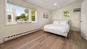 Une chambre avec une grande fenêtre, un lit et un radiateur.