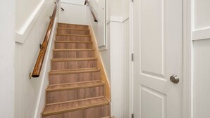 Un escalier en bois, avec des murs blancs et une porte dotée d’une serrure à clé.