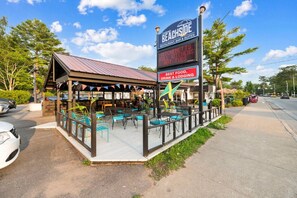 A beachside restaurant with outdoor seating, a digital signboard, and a covered patio area. - 3BR Beach Apartment | The Beachside Co. #12 (Sylvan Beach)