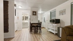 Un espacio habitable compacto con comedor, kitchenette y una pequeña zona de estar.