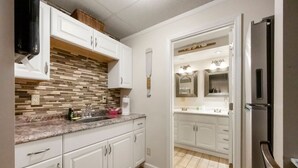 Una cocina moderna con armarios blancos, salpicadero de azulejos y un refrigerador de acero inoxidable.
