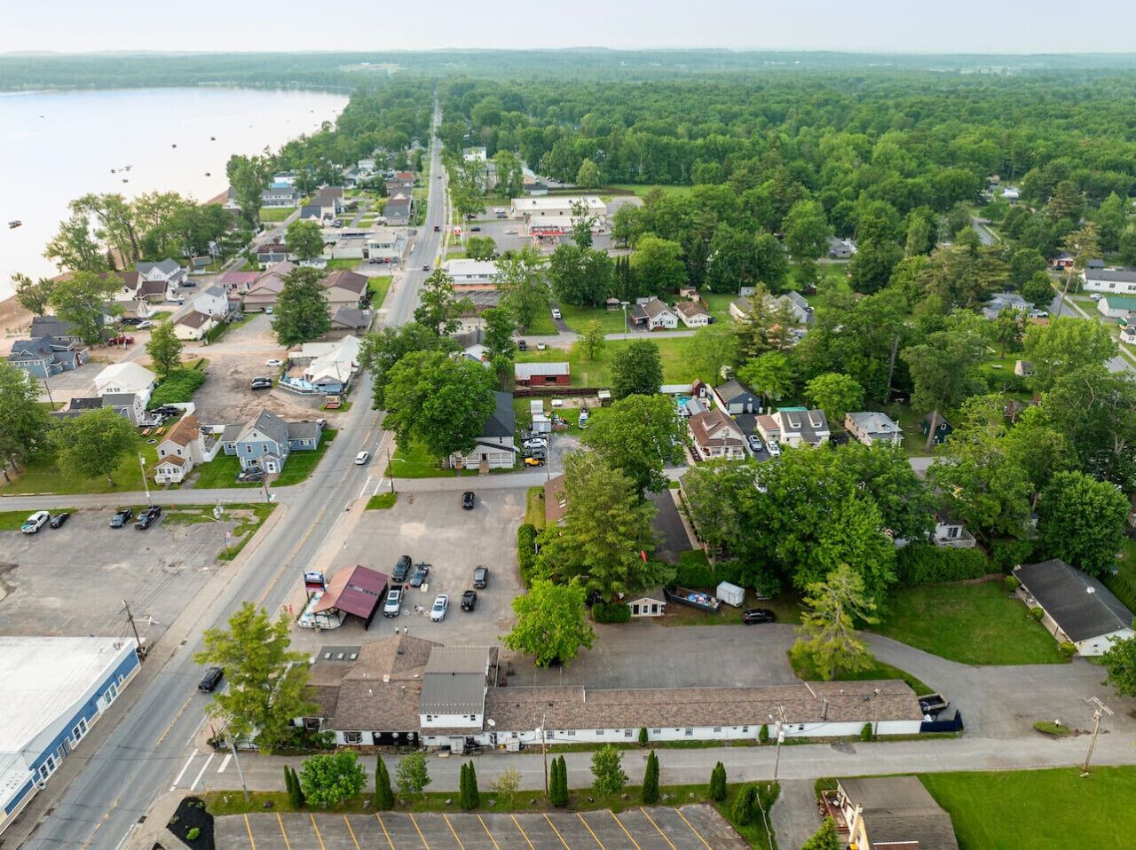 An aerial view of a residential area with houses, a road, and a body of water.