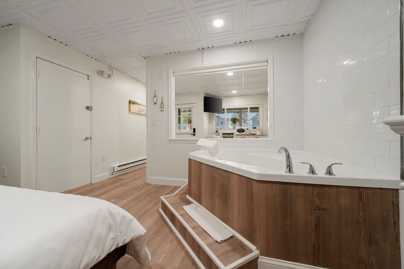 Een moderne badkamer met een vrijstaand bad, een grote spiegel en een houten wastafelmeubel.