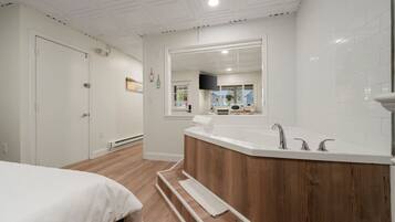 Een moderne badkamer met een vrijstaand bad, een grote spiegel en een houten wastafelmeubel.