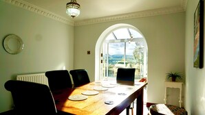 A dining room with a wooden table, black chairs, and a view through an arched window.