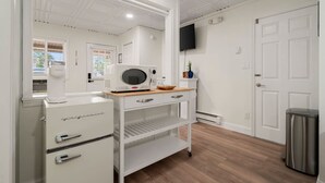Une cuisine compacte avec des meubles blancs, un four à micro-ondes, une machine à café et un petit plan de travail.