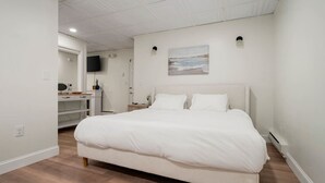 Une chambre avec un grand lit, un bureau avec un ordinateur et un téléviseur à écran plat fixé au mur.