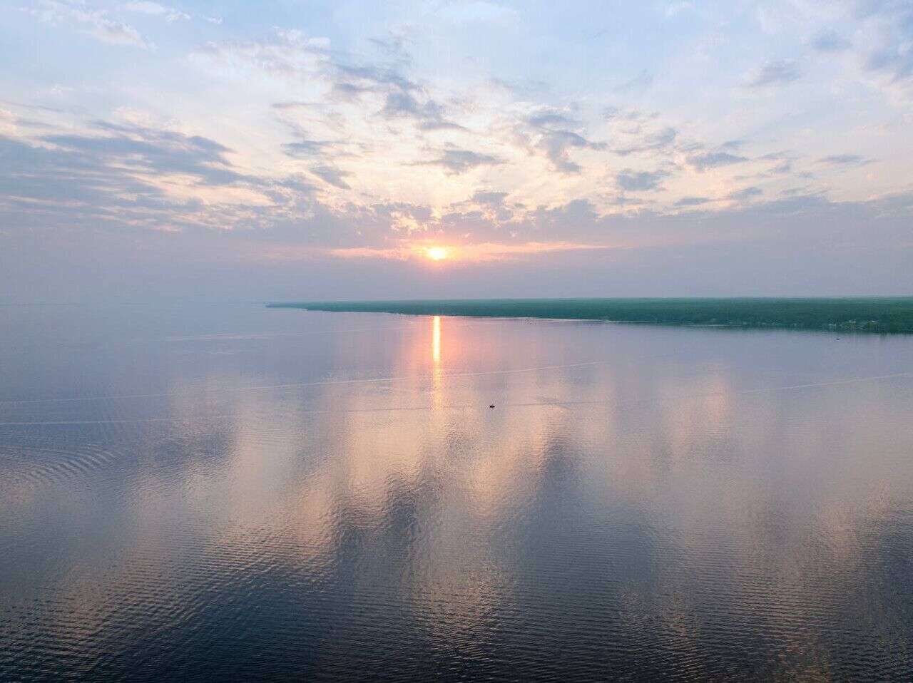 A calm body of water reflecting the sky during sunset.