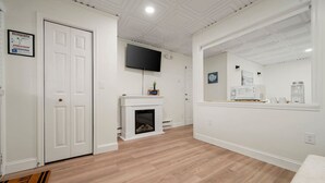 Une pièce dotée d’une cheminée, d’un téléviseur fixé au mur et d’un miroir qui reflète une partie de la pièce.