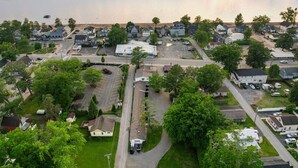 A residential area with houses, a parking lot, and a body of water in the background. - Cozy Beach Studio | The Beachside Co. #6 (Sylvan Beach)