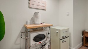 A kitchenette with a coffee maker, a small refrigerator, and a wooden shelf. - Cozy Beach Studio | The Beachside Co. #6 (Sylvan Beach)
