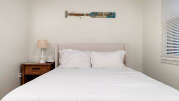 A bedroom with a bed, a nightstand with a lamp, and a wall-mounted item.