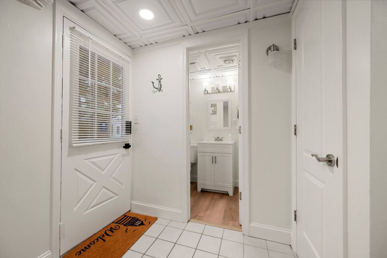 A hallway with white walls, a white door, and a brown doormat.