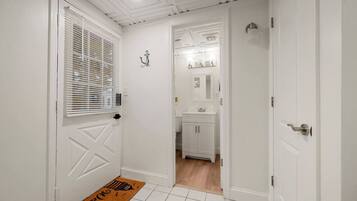 A hallway with white walls, a white door, and a brown doormat.