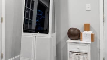 Un meuble de rangement blanc, doté d’un grand miroir et d’une petite étagère sur laquelle se trouvent un ballon de yoga et une boîte.