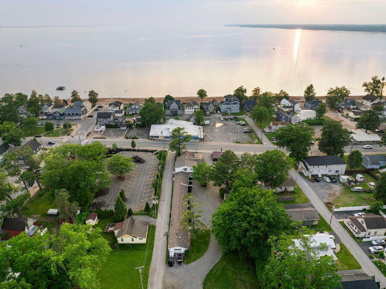A residential area with houses, a parking lot, and a body of water in the background.
