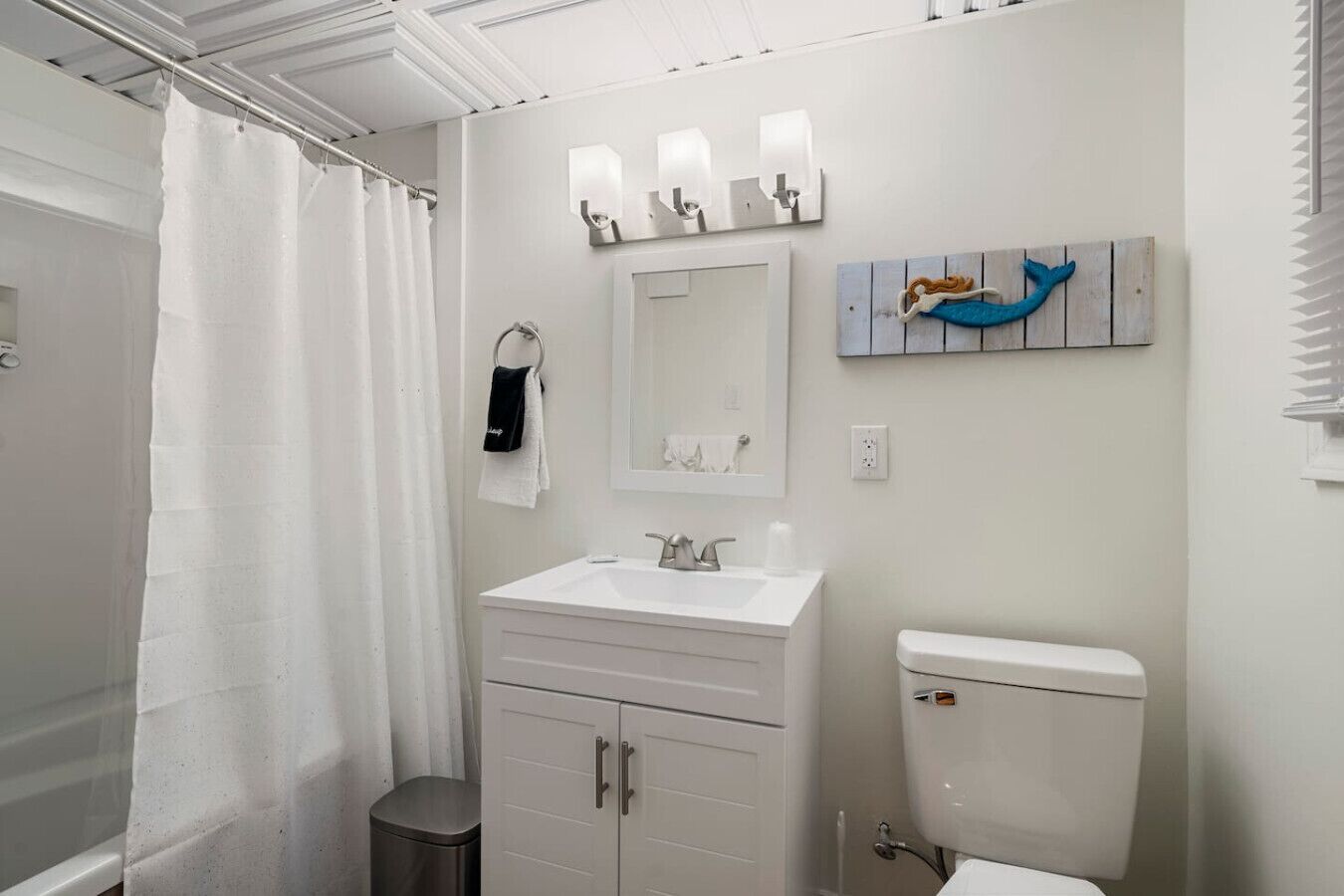 A bathroom with a shower, a sink, a toilet, and a towel rack.