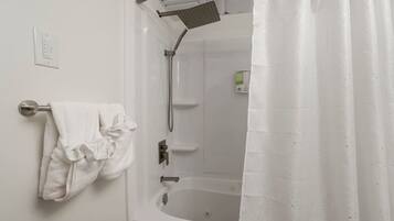 A bathroom with a bathtub, a showerhead, a towel rack with a towel, and a control panel.