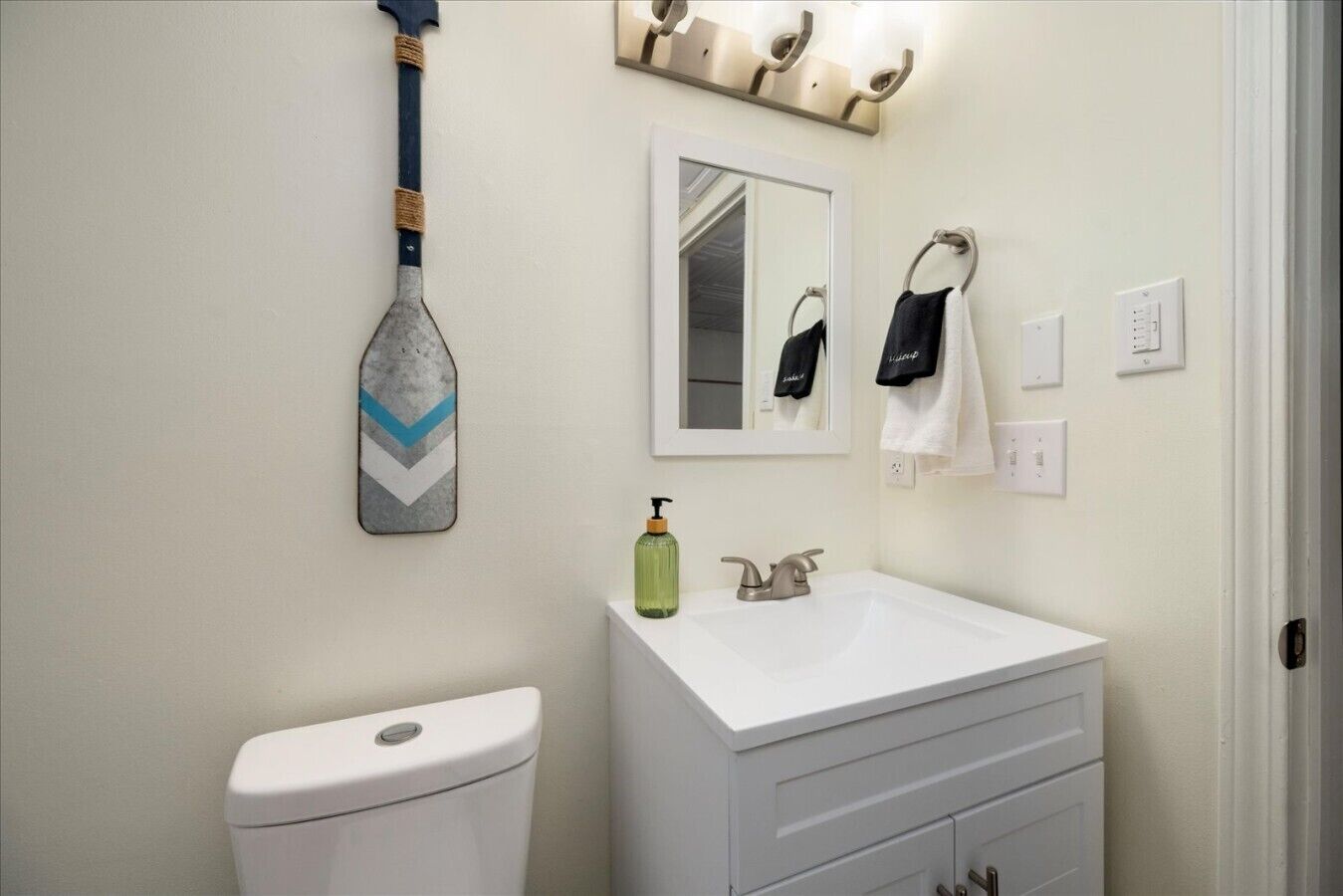 A bathroom with a toilet, a sink, a mirror, and a towel rack.