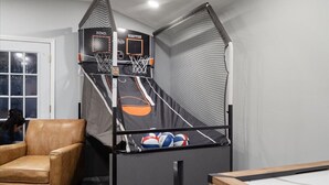 Una habitación con aro de baloncesto, una silla y una mesa de billar.
