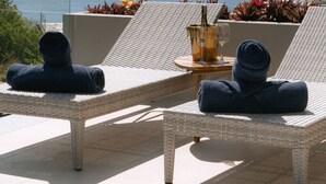 A sunlit outdoor seating area with wicker lounge chairs, a table with a drink and a glass, and a view of the sea. - Villa Jaisai 4-bedroom Sea View & On-Site chef (Chaweng)