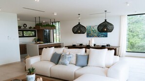 A modern living room with a sectional sofa, a coffee table, and a dining area with a table set for four. - Villa Jaisai 4-bedroom Sea View & On-Site chef (Chaweng)