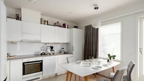 Een moderne keuken met witte kasten, een eettafel met stoelen en een raam met gordijnen.