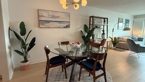 Un espace repas comprenant une table ronde en verre, des chaises en bois et un luminaire suspendu au plafond.