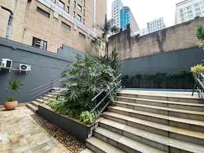 A set of outdoor stairs leading up to a building entrance, surrounded by greenery and modern architecture.