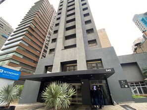 Ein modernes Gebäude mit einem markanten Eingang, einem Schild mit der Aufschrift 'Wyndham São Paulo Paulista' und der Nummer 540 an der Fassade.
