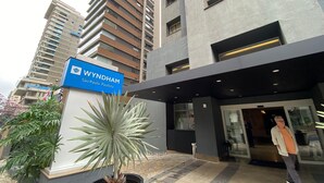 Eingang eines Wyndham Hotels mit moderner Fassade, einem Schild und einem Blumentopf.