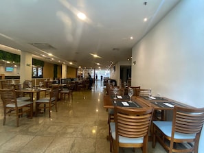 Ein geräumiges Restaurant mit mehreren Tischen und Stühlen, einem sauberen Fliesenboden und freundlicher Atmosphäre.