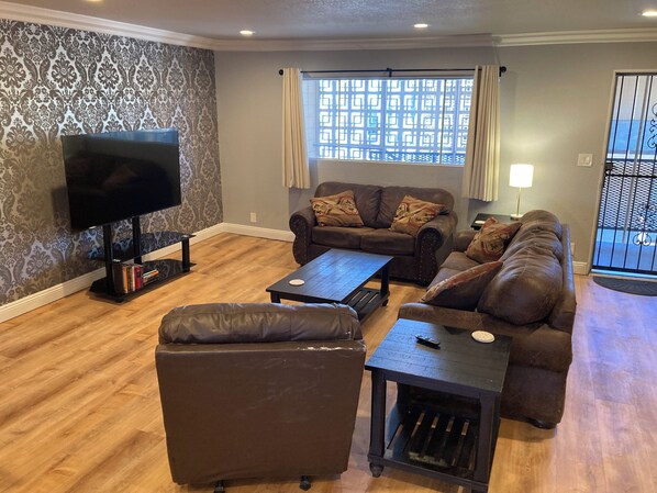 A living room with a flat-screen TV, two sofas, a coffee table, and a patterned wall. - 3-bedroom walking distance to strip. (Las Vegas)