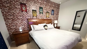 A bedroom with a brick wall, a wooden headboard, a bed with white bedding, two bedside tables with lamps, and a mirror on the wall. - Comfy Villa 3BR Near Disney & Parks (Kissimmee)