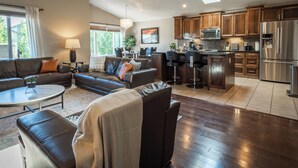 A modern living room with a sofa, coffee table, and a dining area with chairs. - Modern Comfort, cozy family home for work & leisure in the luxurious Southside (Lethbridge)