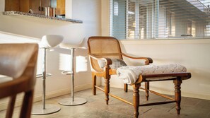 A room with a wooden chair, a floor lamp, and a window with blinds.