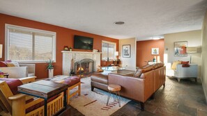 A living room with a fireplace, sofa, coffee table, and a dining area with a table and chairs.