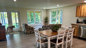 Une cuisine spacieuse avec un coin repas, des meubles en bois et une grande fenêtre donnant sur l’extérieur.