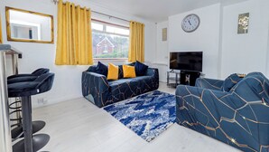 A modern living room with a sofa, TV, and a window with curtains.