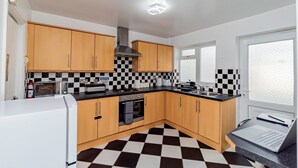 A modern kitchen with wooden cabinets, a black and white checkered floor, a built-in oven, and a laptop on the counter.