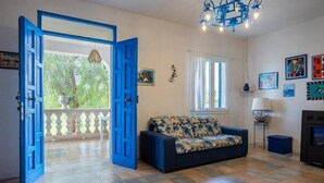 A living room with a blue sofa, a fireplace, and a balcony with a view of greenery. - [Shell House] AC|Wi-Fi|P private|BBQ (Castelvetrano)