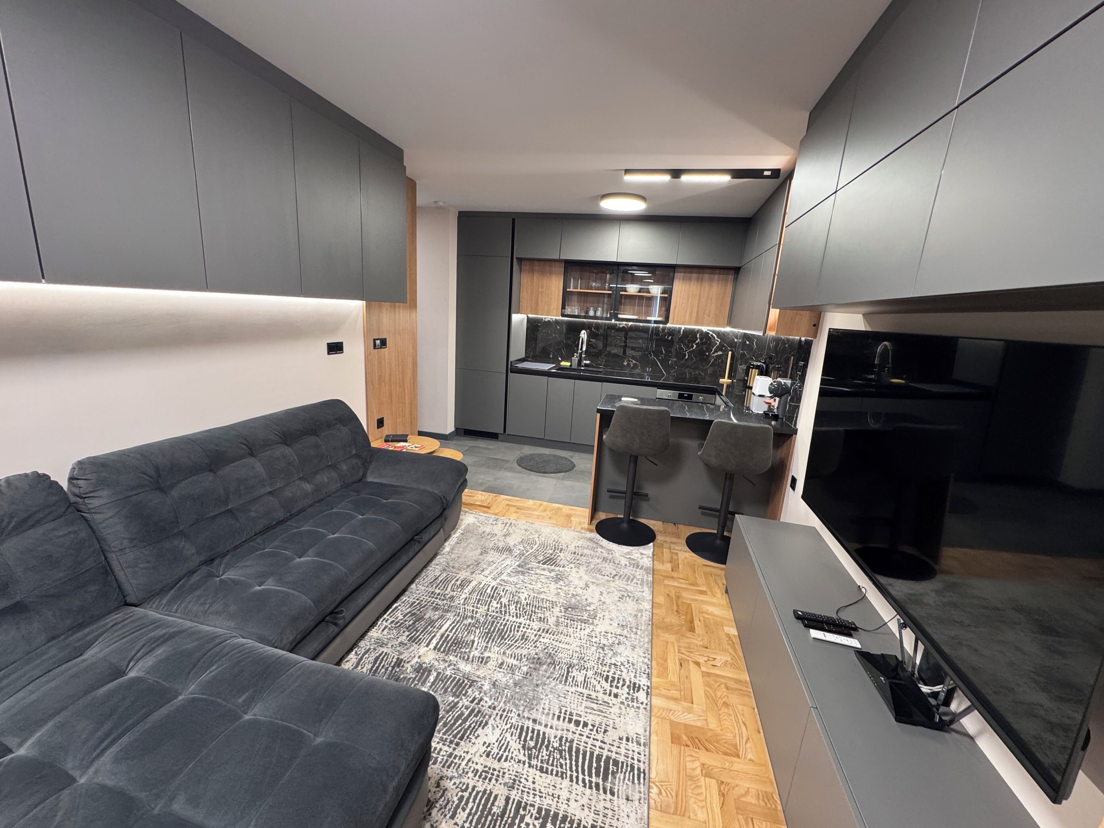 A modern kitchen with grey cabinets, a black countertop, and a built-in oven.